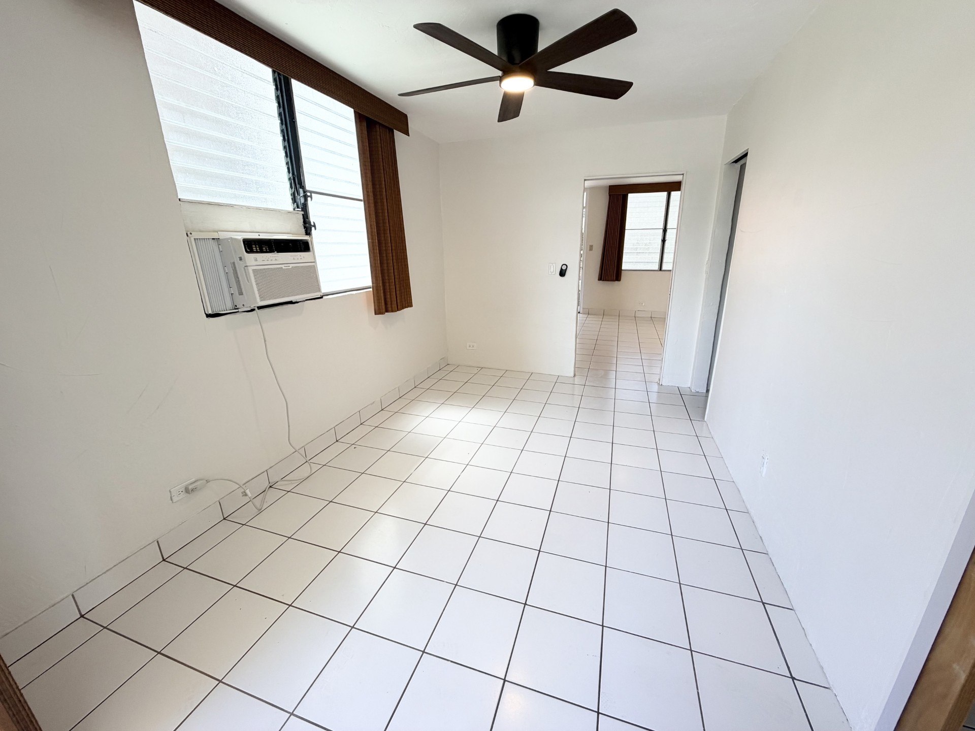 A room with a ceiling fan and tiled floor.